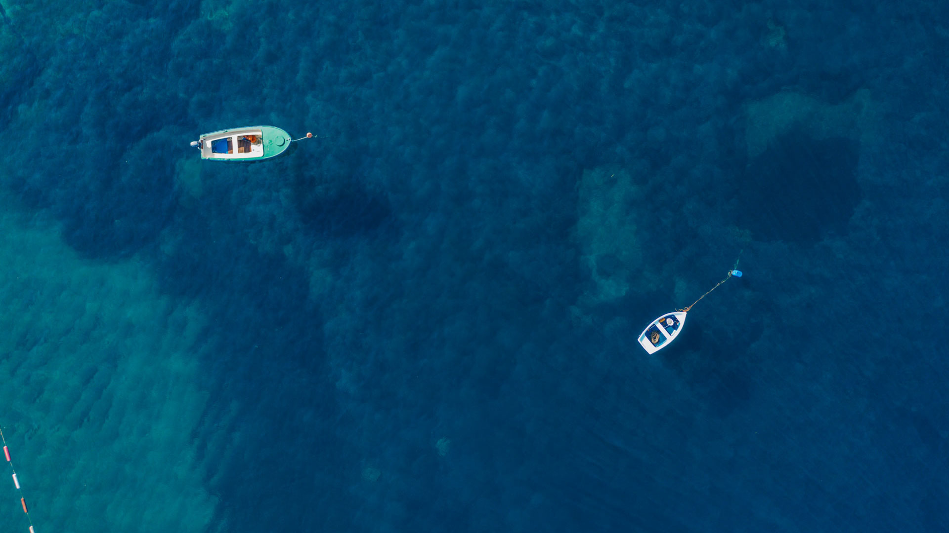 Aerial view of small boats floating in the clear Adriatic waters at Aman Sveti Stefan, Montenegro