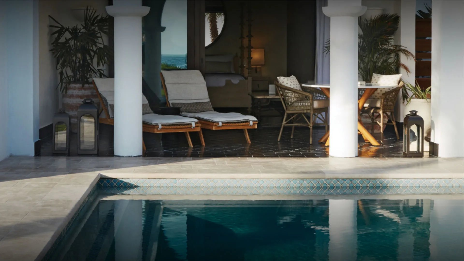 Private plunge pool and shaded patio suite at Belmond Cap Juluca, with lounge chairs, lanterns, and an open bedroom beyond.