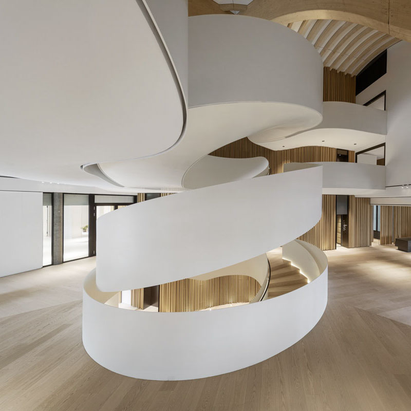 Curved staircase beneath the timber-ribbed atrium ceiling at Lanserhof Sylt