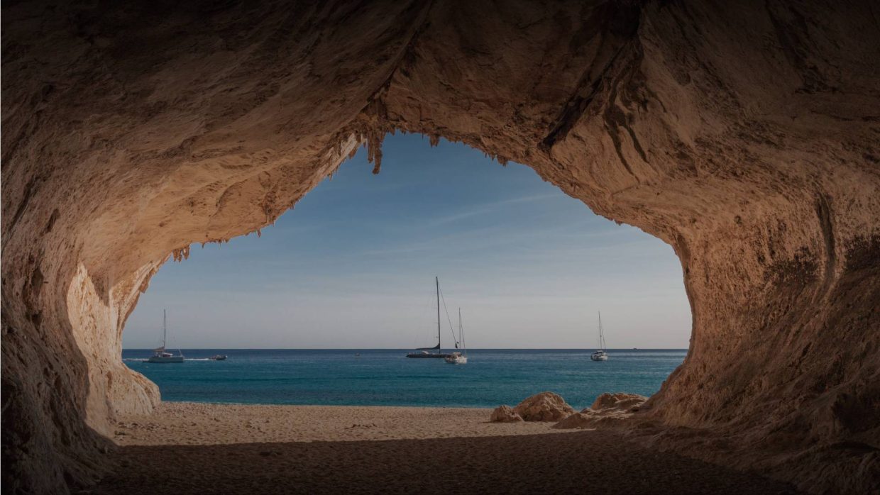 Beach cave framing yachts at anchor in the turquoise bay near Hotel Cala di Volpe, Sardinia