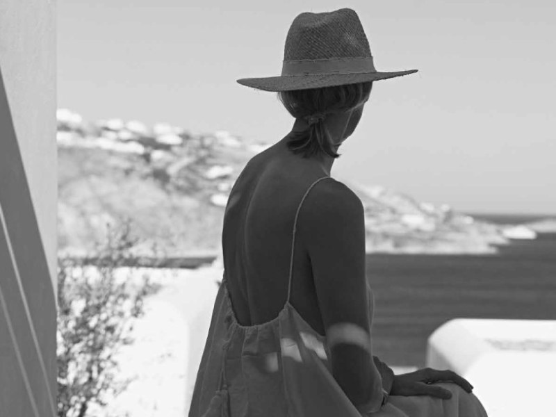 Guest in a straw hat looking across the bay from Kalesma Mykonos