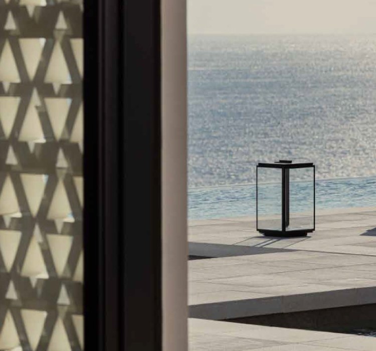 Lantern beside the infinity pool at Kalesma Mykonos, seen through a latticed screen
