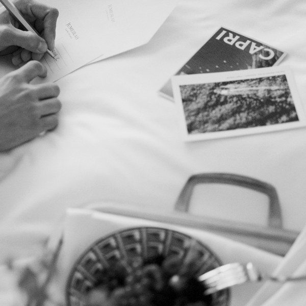 Guest writing a postcard over breakfast in bed at Capri Palace Jumeirah