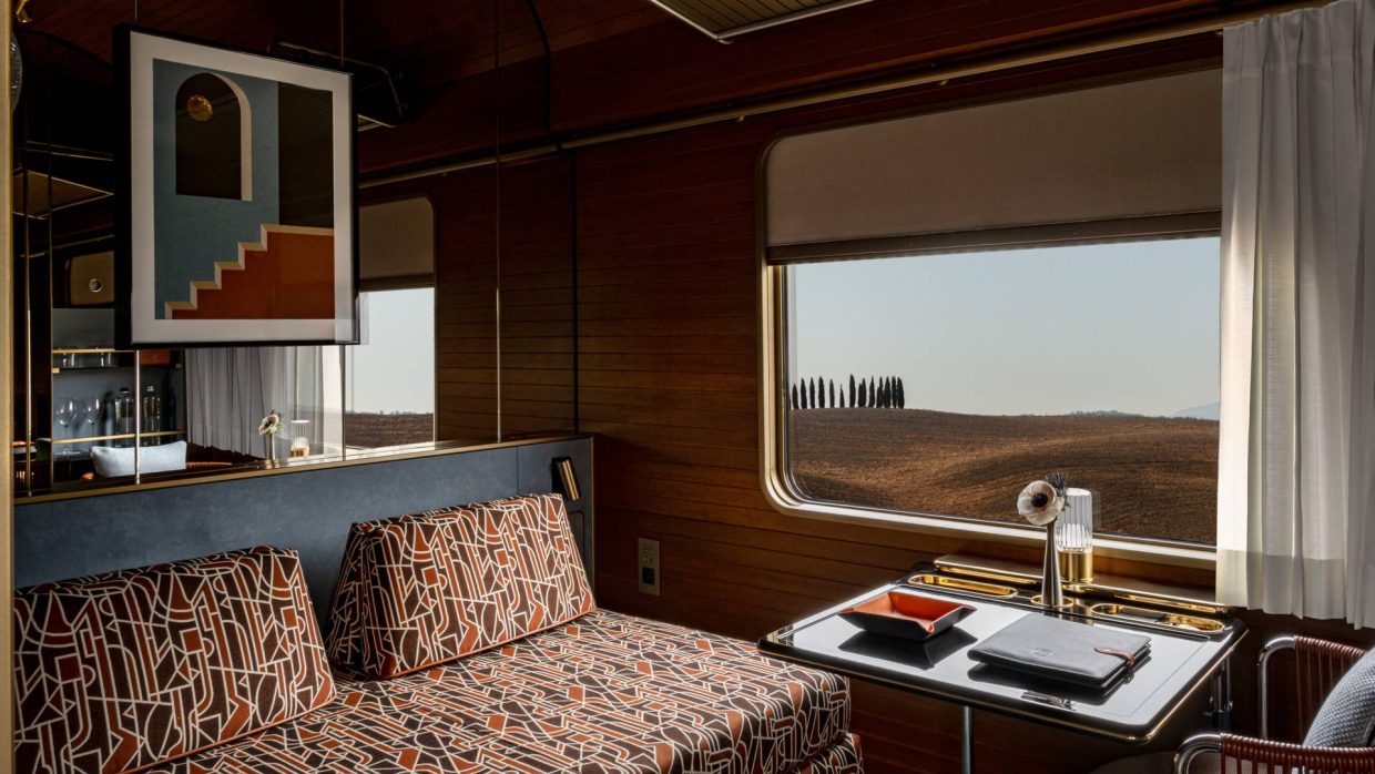 Suite interior with cypress-lined Tuscan hills through the window on La Dolce Vita Orient Express