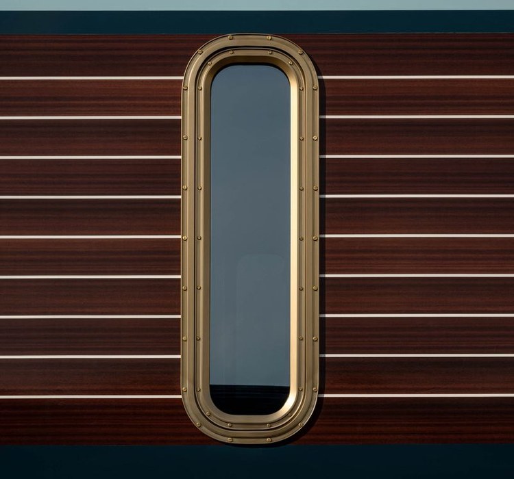 Porthole window and walnut stripes on the exterior of La Dolce Vita Orient Express