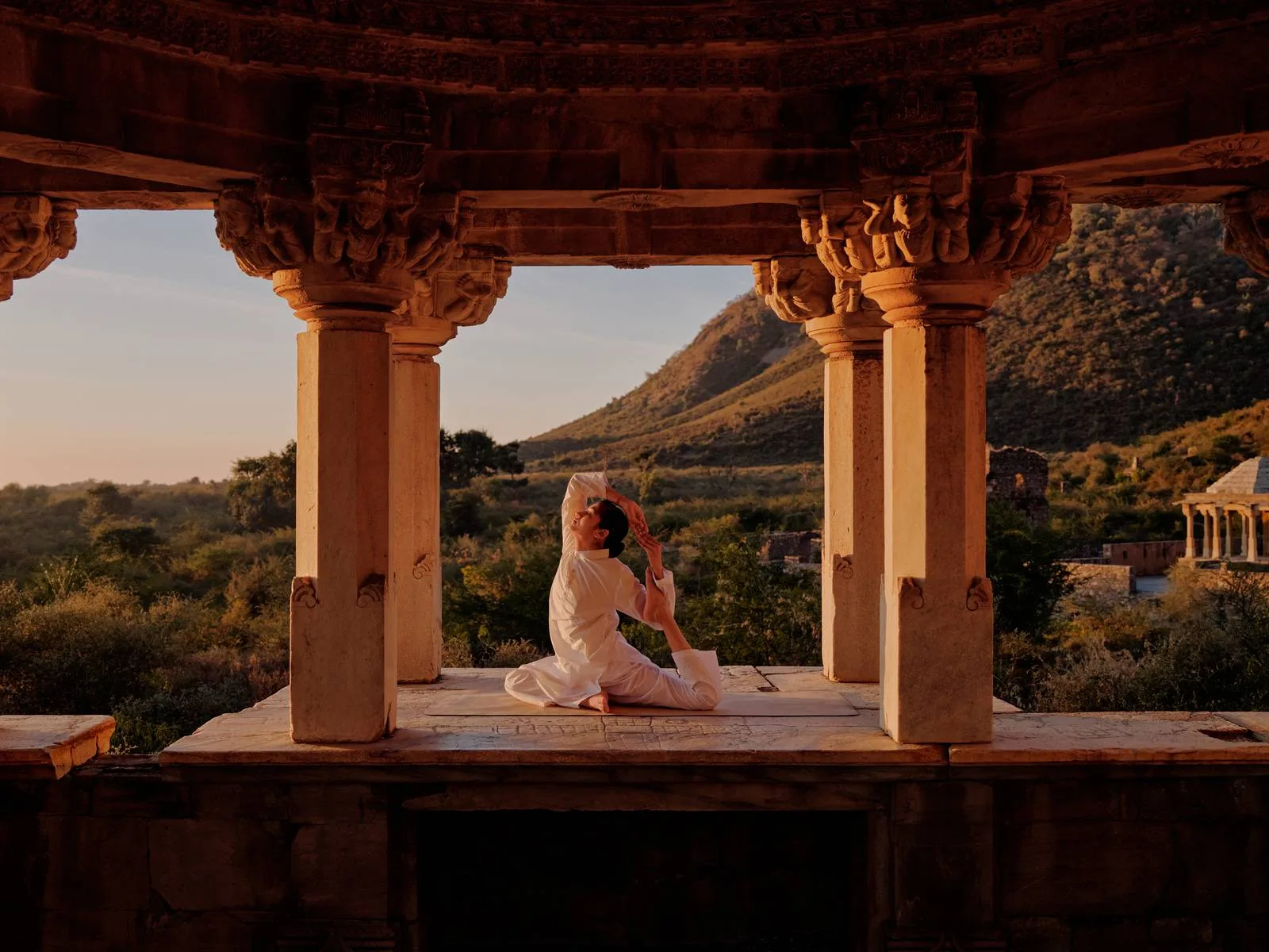 A yoga pose beneath a carved stone pavilion at the ruined city of Bhangarh, near Amanbagh, Rajasthan