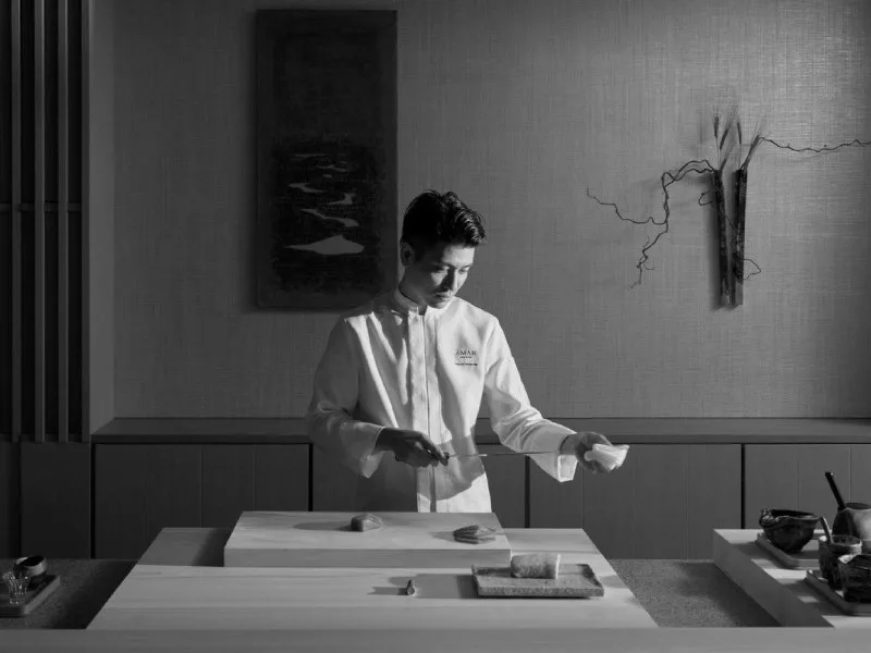 A chef at work behind the counter of the sushi restaurant at Aman New York, in black and white