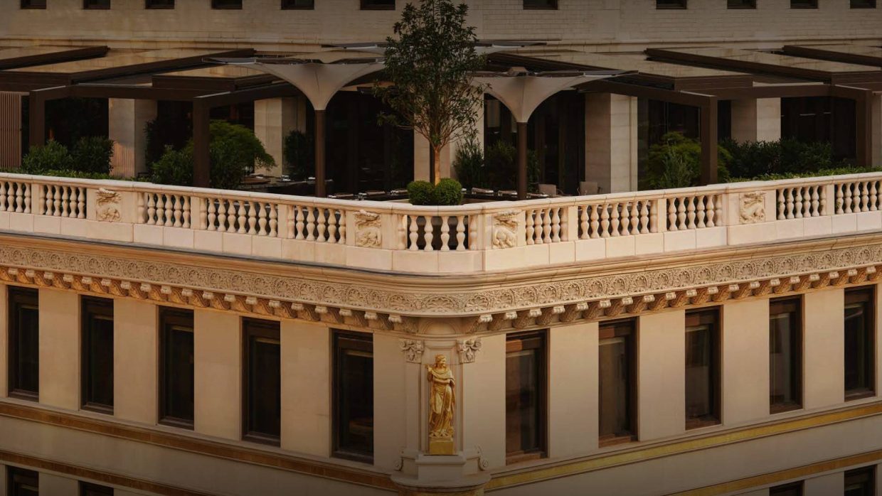 A roof terrace and stone balustrade above a gilded statue on the hotel's facade