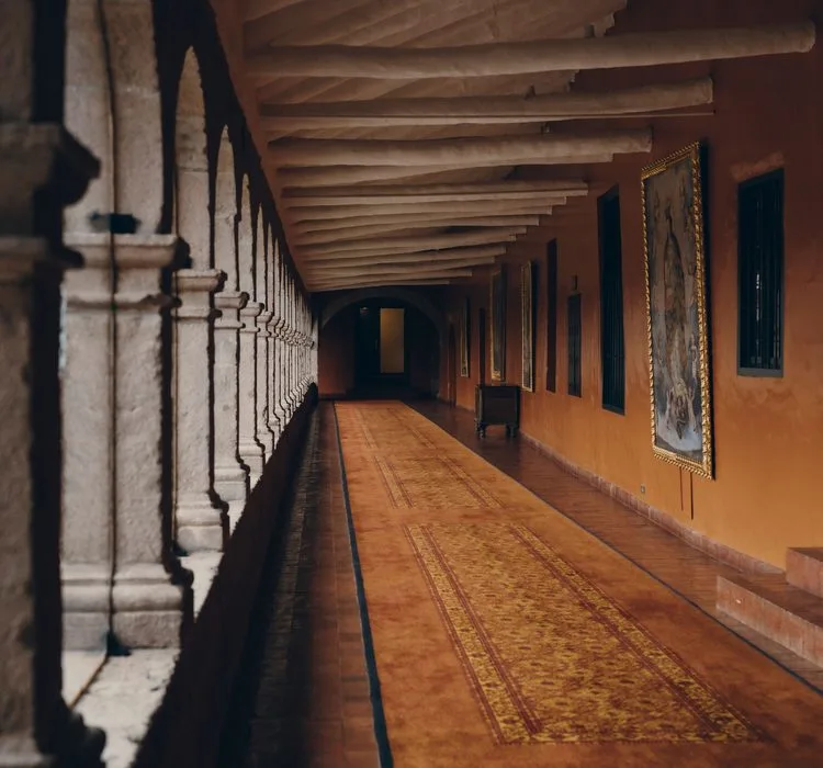 An empty stone arcade with a patterned runner receding into the distance