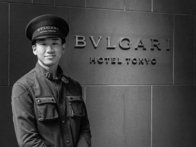Doorman in Bulgari uniform beside the Bulgari Hotel Tokyo entrance sign