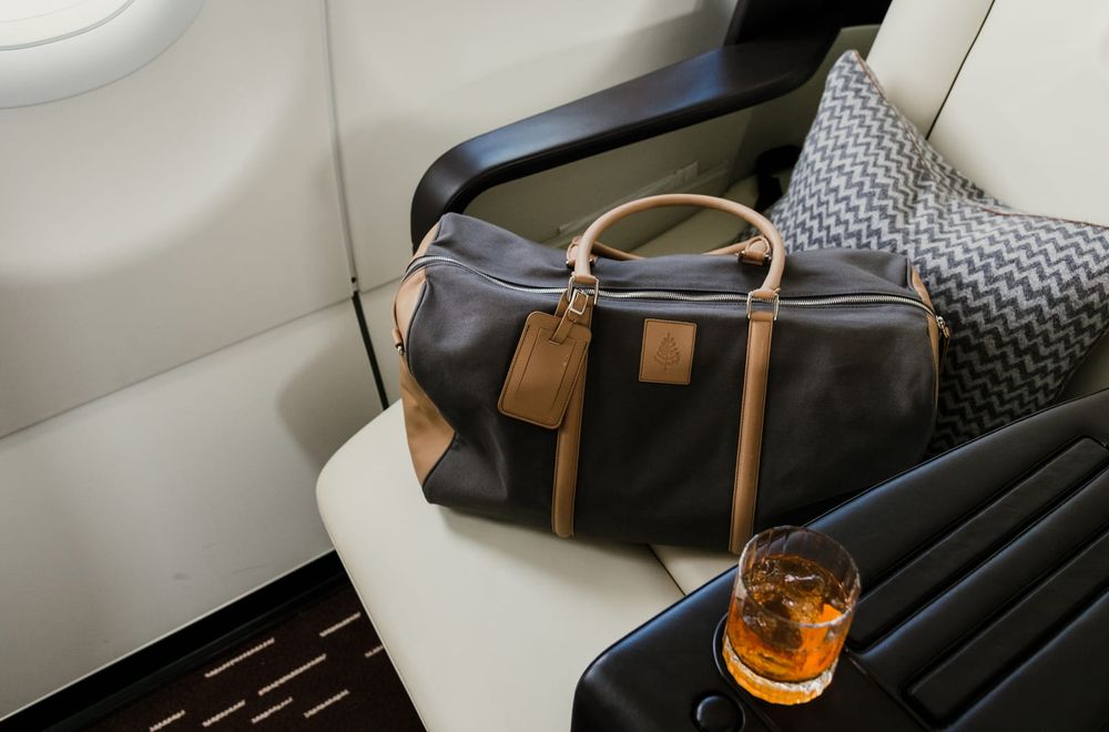 A leather duffel bag and a whisky on the arm of a cabin seat