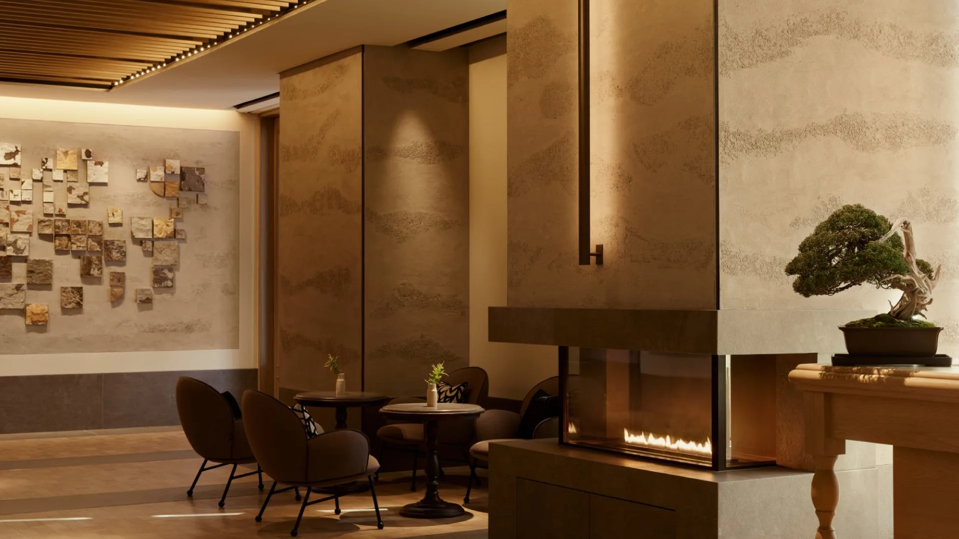The lounge at Janu Tokyo with a lit fireplace, a bonsai and a fossil stone wall
