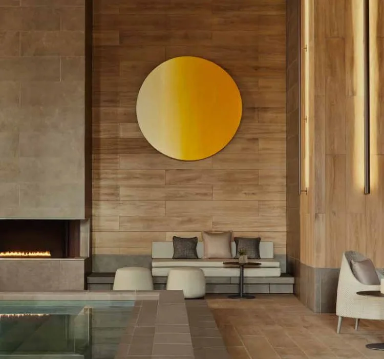 A gold circular artwork above a low bench beside the indoor pool at Janu Tokyo