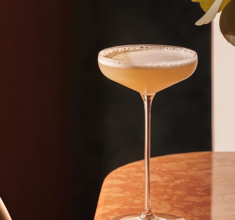 A coupe cocktail catching the light on a russet marble table at Jumeirah Marsa Al Arab