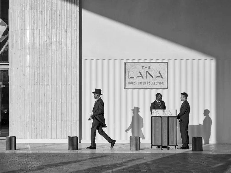 Doorman and valets beneath The Lana's sign in golden-hour light, mono