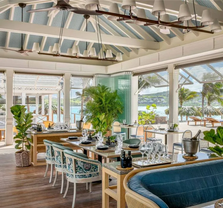 La Table du Guanahani restaurant with blue banquettes, tropical plants and open windows