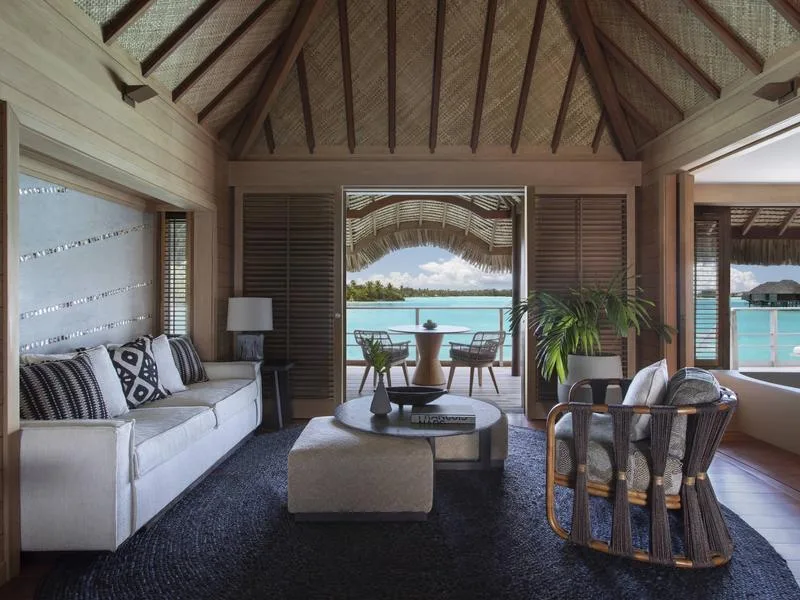 Overwater bungalow living room with wooden beams and lagoon views at Four Seasons Resort Bora Bora