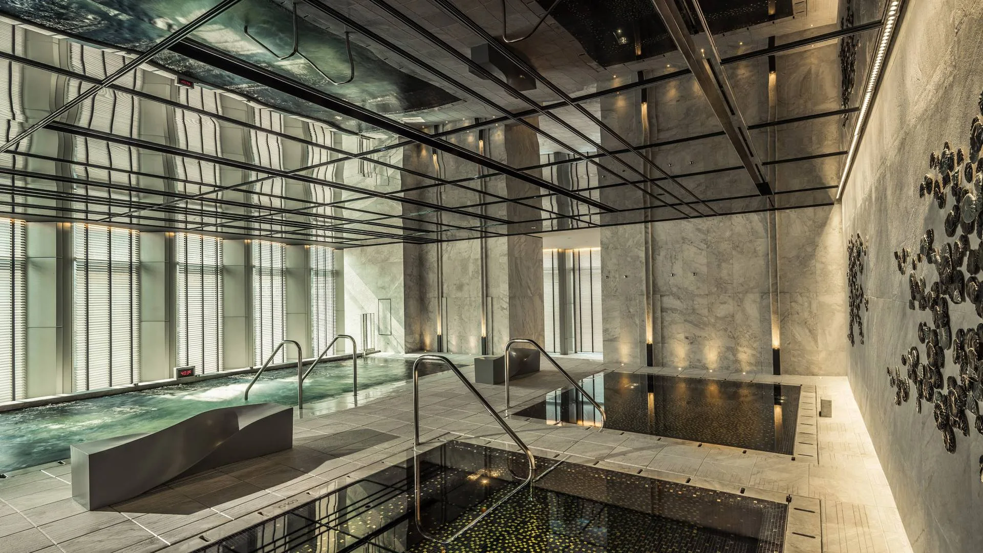 The stone-lined spa pools beneath a grid of lights, reflected in dark water