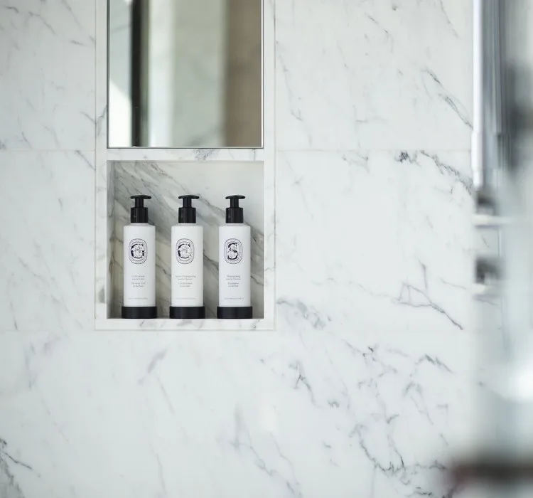Three bath bottles in a niche of white marble in a guest bathroom at Four Seasons Hotel Seoul